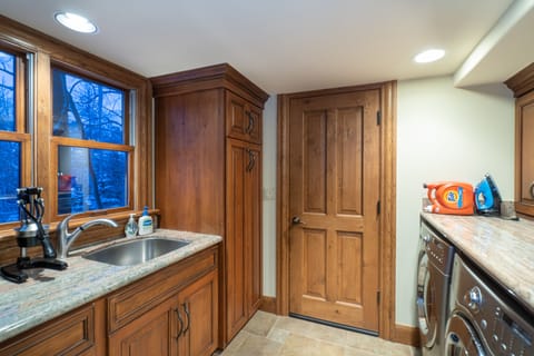 Laundry room with sink and stainless steel washer and dryer.