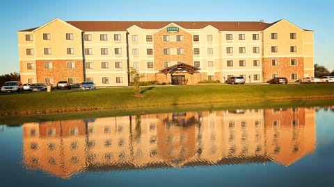 Exterior view at dusk with pond reflection and parking — the hotel is lit and staffed for late arrivals