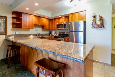 Your fully equipped kitchen features rich wood cabinetry, granite countertops, and modern stainless steel appliances. Gather around the breakfast bar to plan your island adventures or prepare meals together in this inviting space.