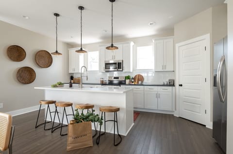 Kitchen features modern appliances and an island with barstool seats.