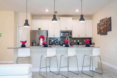 Start your day in this sleek modern kitchen with bar seating for four, glossy finishes, and all the essentials for a delightful group breakfast!