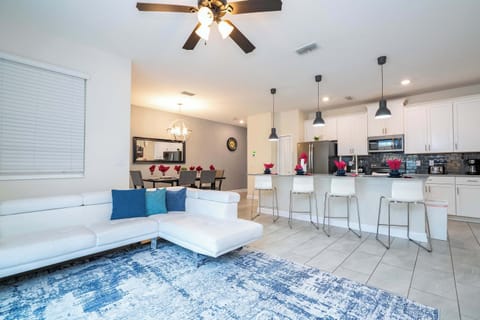 Gather in the spacious open-plan living area, featuring a modern sectional, colorful rug, and easy flow to the kitchen and dining spaces-perfect for group fun!