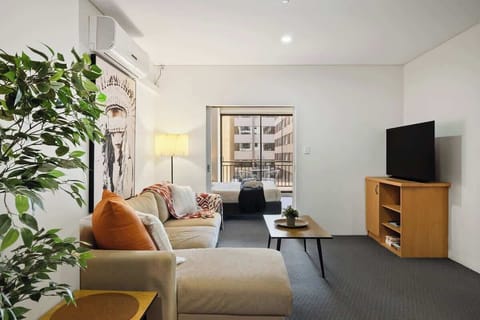 Your cozy home away from home. Unwind on the plush sofa, watch the flat-screen TV, or step onto the balcony for fresh air. The open layout offers a view of the comfy bed, with a touch of greenery to brighten the space.