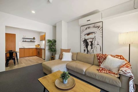 Your relaxing stay starts here. Enjoy our comfortable living room with its spacious sofa, unique artwork, and a view into the handy kitchen area. Everything you need to feel right at home.