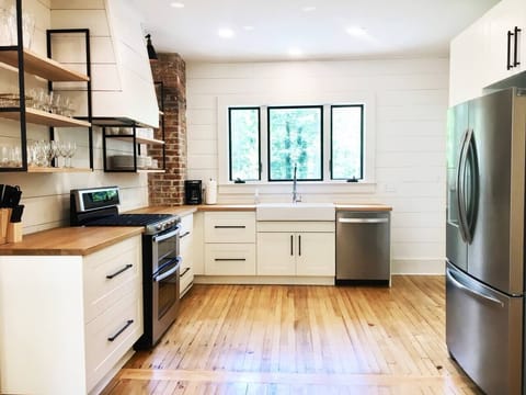 Farmhouse sink and open shelving with original brick column exposed