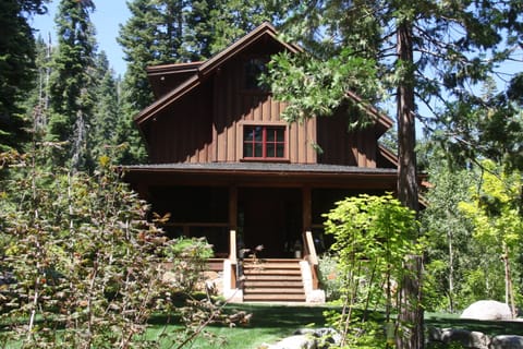The main house with its covered front porch on the lawn, overlooking the forest