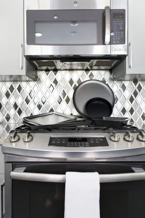 Galley-style, fully equipped kitchen with an open-concept flow to the living/dining area. Stocked with essentials, stainless steel appliances, stone countertops, and a tile backsplash for a luxurious feel!