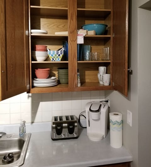 Cupboards stocked with dishware, silverware, pots & pans for cooking. 