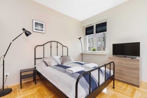 Studio with comfortable and stylish double bed, television for evening relax, elegant lamp, and capacious cabinet.