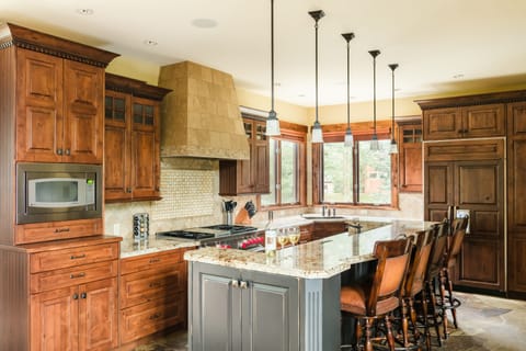 Kitchen features state of the art appliances, an island with barstool seating, and marble countertops thorughout.