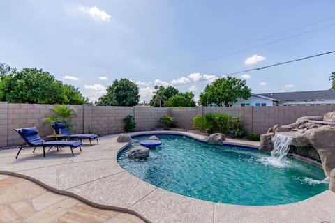 Stunning backyard retreat featuring a private pool with a waterfall, sun loungers, BBQ grill, outdoor seating, Smart TV, and an outdoor dining area.