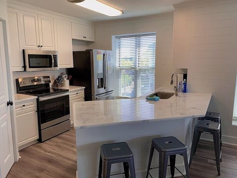 Kitchen with stainless steel appliances and prep island with seating. 208 1140 Ocean Blvd, Isle of Palms, SC | IOP Escapes