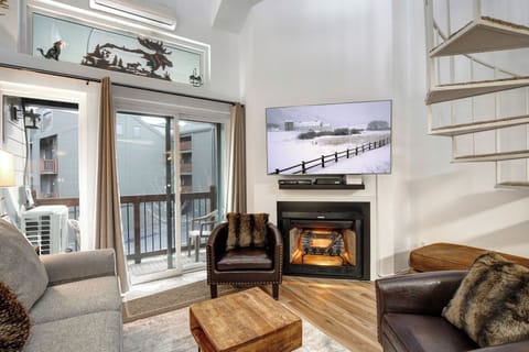 Relax in your stylish living room featuring a cozy fireplace, modern furnishings, and large TV for the perfect evening retreat after your mountain adventures.