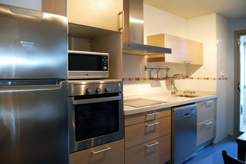 Modern, compact kitchen characterized by light wood fronts and high-quality stainless steel appliances. Efficient design that maximizes functionality and vertical storage.