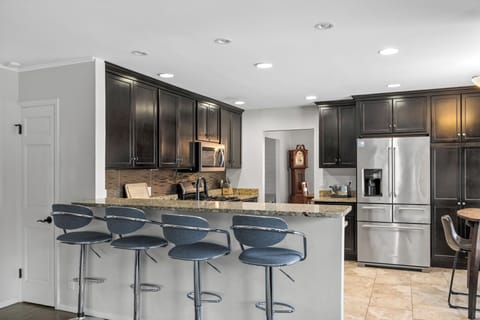 Fully equipped kitchen with stainless steel appliances and seating for 3 people and a bar with 4 stools 