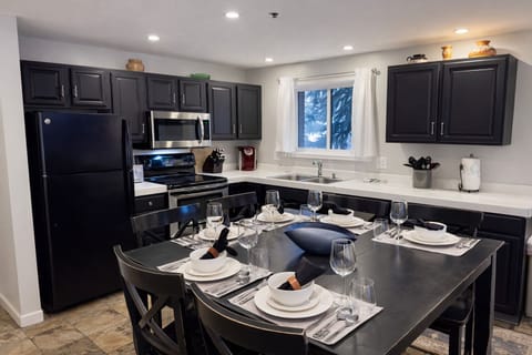 Your elegant kitchen awaits with sleek dark cabinets, modern appliances, and a welcoming dining space set for memorable meals together.