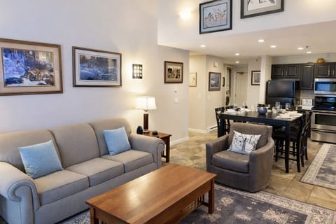 Cozy mountain living room with a stone fireplace, comfy sofa, and balcony access.
