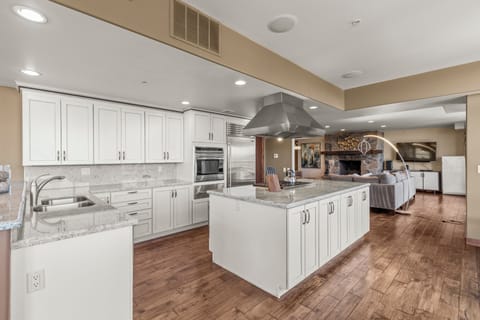 The spacious kitchen has many white cabinets, a wrap around counter and breakfast bar, and freestanding island.