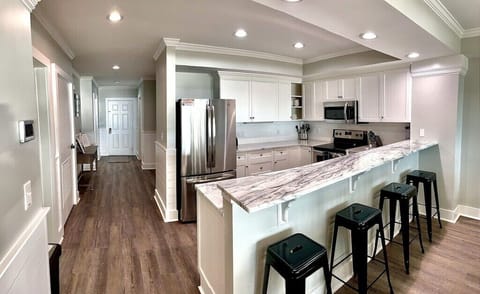 Kitchen with stainless steel appliances and prep island with seating. Dunescape 101 IOP Escapes
