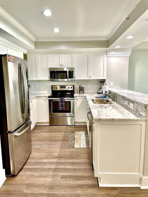 Kitchen with stainless steel appliances and prep island with seating. Dunescape 101 IOP Escapes