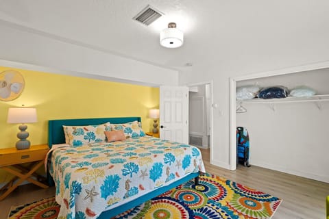 Siesta Key beach retreat master suite with coral linens, golden accents, and a whimsical rug—crafted for cheerful rest and effortless coastal charm.