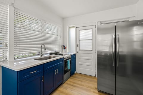 Siesta Key beach kitchen with stainless steel fridge, ocean-blue cabinets & bright prep area—designed for effortless cooking and coastal comfort.