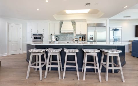This modern kitchen features sleek stainless appliances, a spacious island with stylish seating, and a view of the beach
