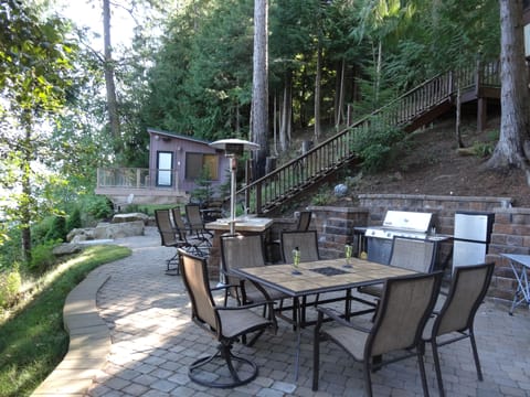 Outdoor kitchen with BBQ, fridge, patio heaters, speakers, Solo Stove fire pit.