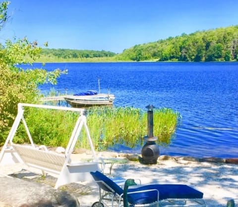 sandy beach with swing, chaise lounges, table and chairs, fire pit