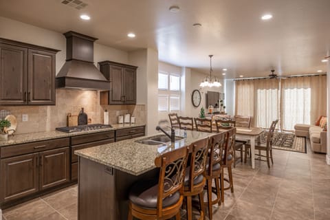 Kitchen View - The Kitchen and Dining Table can accommodate 10 adults and is stocked with pots, pans, baking sheets, mixing bowls, plates, bowls, cups, silverware, and a collection of cooking utensils.