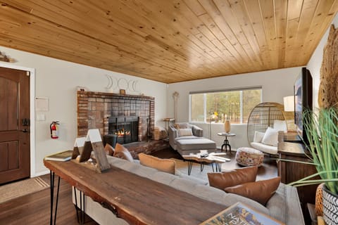 Cozy mountain living room with a stone fireplace, comfy seating, and smart TV—perfect for relaxing evenings, movie nights, and warm cabin vibes after outdoor adventures.