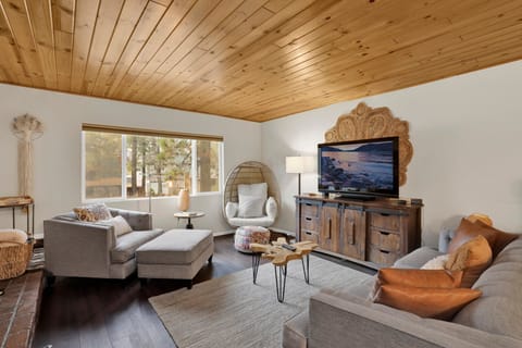Cozy mountain living room with a stone fireplace, comfy seating, and smart TV—perfect for relaxing evenings, movie nights, and warm cabin vibes after outdoor adventures.