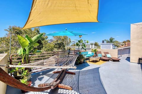 Stunning rooftop oasis with a hammock, lush greenery, cozy lounge seating, and a sunshade for ultimate relaxation.