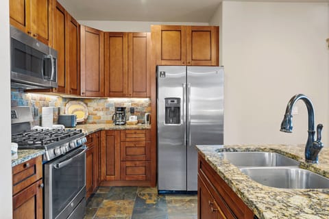 The kitchen features granite countertops, stainless steel appliances, and breakfast bar seating.