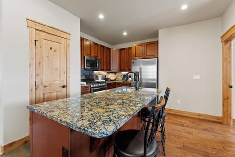 The kitchen features granite countertops, stainless steel appliances, and breakfast bar seating.