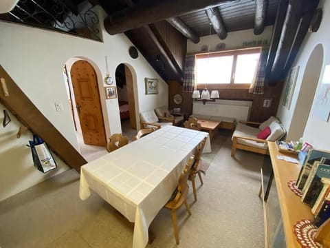View of the dining table and the living room, the stairs / ladder to the gallery and the two bedrooms on the left