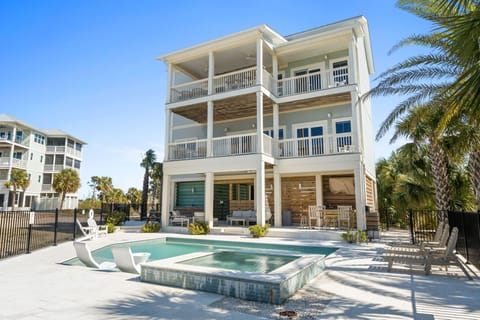 Modern three-story beachside property featuring private pool, hot tub, and tropical landscaping in a coastal community setting.