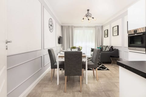 A dining area with a round table set for two, located next to the open-plan kitchen. The space has modern decor and warm lighting.