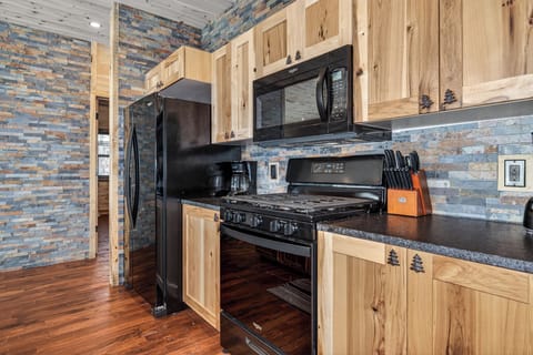 Your fully equipped kitchen blends rustic charm with modern convenience, featuring natural wood cabinets and stunning stone backsplash.
