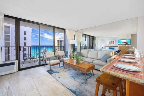 Spacious living area bathed in natural light w/ floor-to-ceiling windows.

