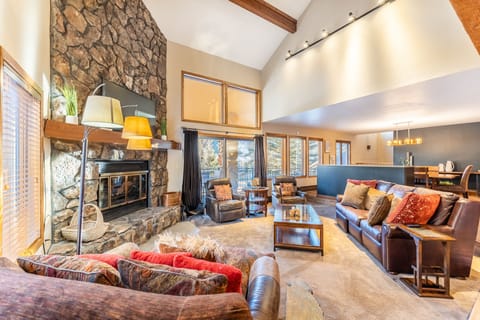 Unwind in your spacious living room featuring a stunning stone fireplace, vaulted ceilings, and cozy leather seating perfect for mountain evenings.