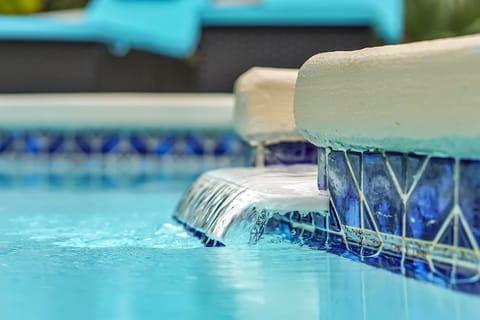 The waterfall spills over from the small section into the main pool