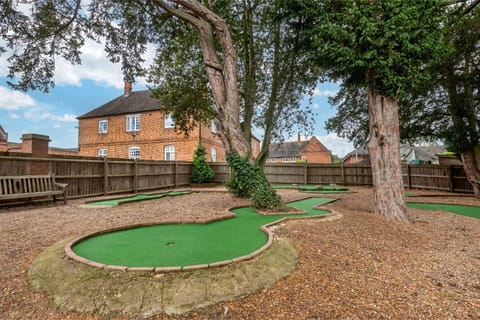 A tranquil garden area with a miniature golf course set under the shade of mature trees.