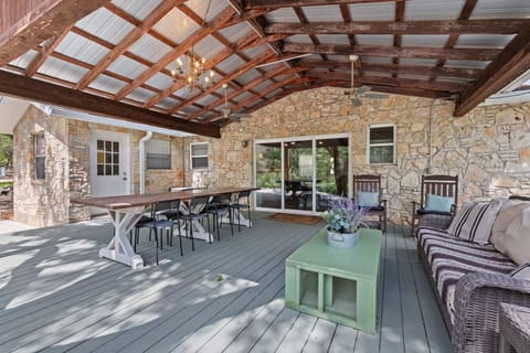 The Lazy Lavender Farmhouse in Wimberley Texas — Covered Outdoor Porch with Farm Dining Table Seats 8 and Stone Wall