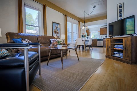 Comfy living room with leather seating, smart TV, and tall ceilings.