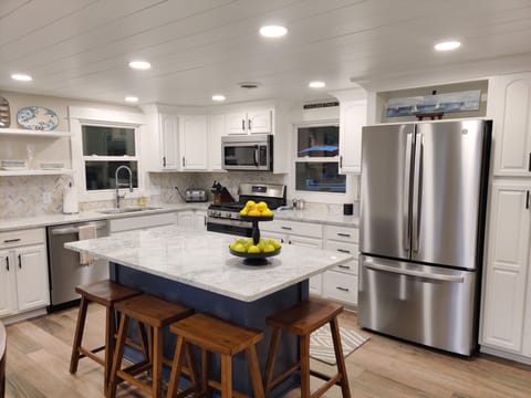 Spacious kitchen with a large island, stainless steel appliances and dishwasher.