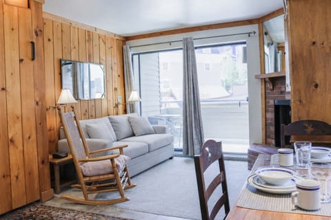 Cozy mountain living room with a stone fireplace, comfy sofa, and balcony access.