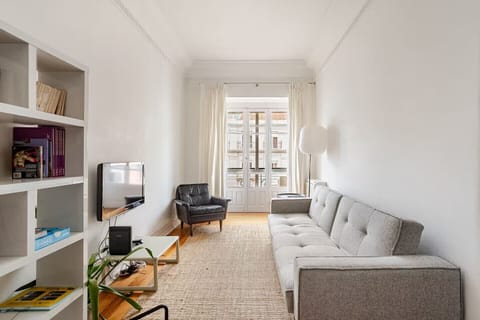 Bright living room with a comfortable sofa, TV and access to a sunlit balcony.