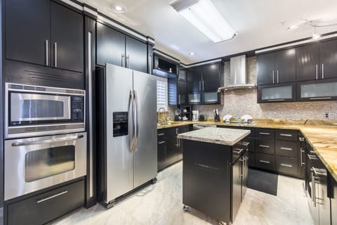 The modern kitchen is fully stocked with pots, pans and cooking utensils