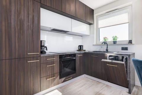 A sleek kitchen featuring wooden cabinets, white countertops, and modern appliances. The design is contemporary and minimalistic.